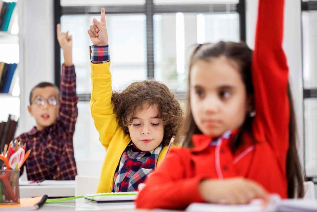Children in elementary school raising their hands to answer