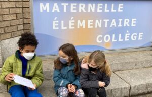 A 6th grader of The French American Academy reading his self-created book to a 1st grader in front of the Jersey City building.